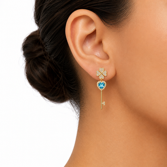 Close-up of an ear wearing a decorative earring with a blue gemstone on a white background