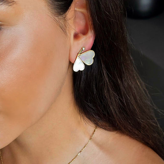 Butterfly-shaped earring worn by a person with dark hair.