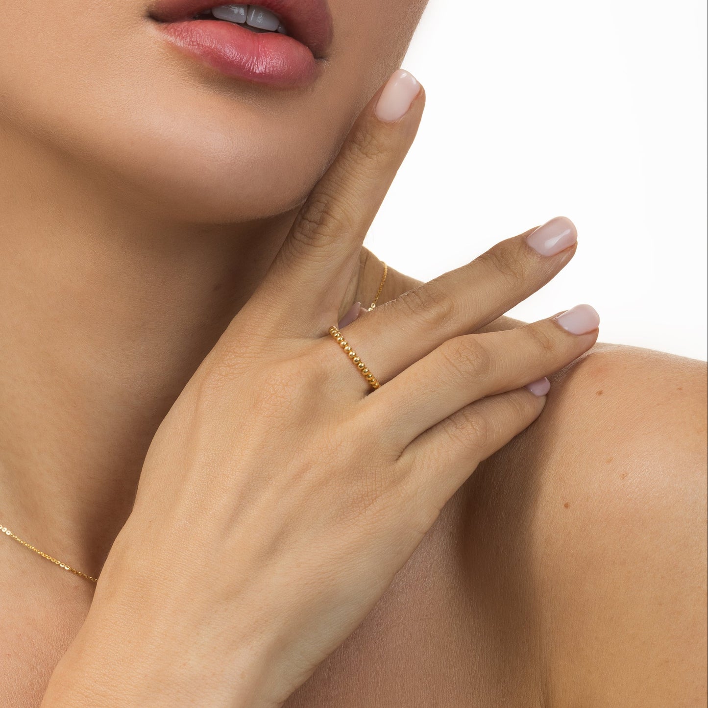 Close-up of a woman's hand wearing a gold ring on a white background