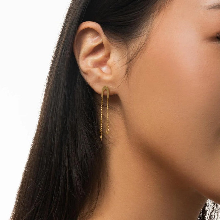 Close-up of a woman wearing gold earrings and necklace on a white background