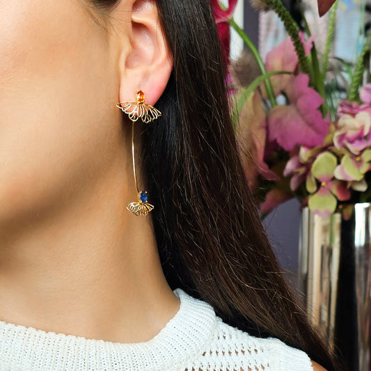 Close-up of a person wearing gold earrings with a floral background