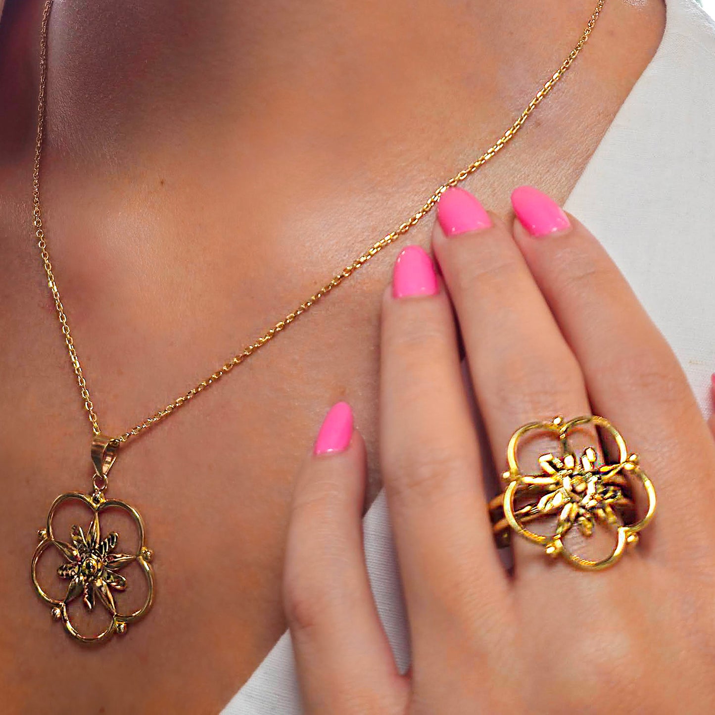 Gold necklace and ring with floral design worn by a person