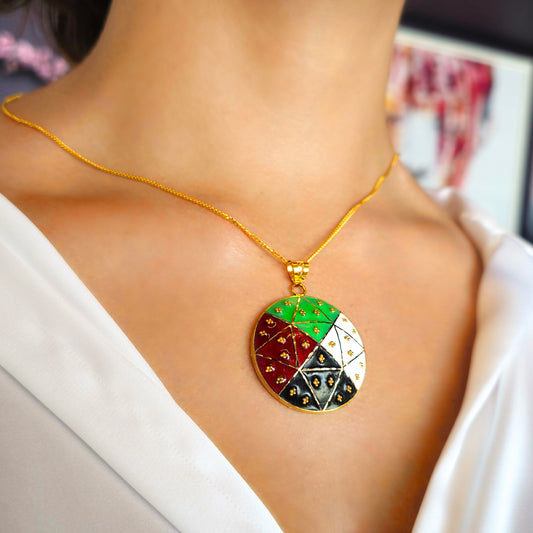 Gold necklace with a colorful pendant on a person wearing a white top.