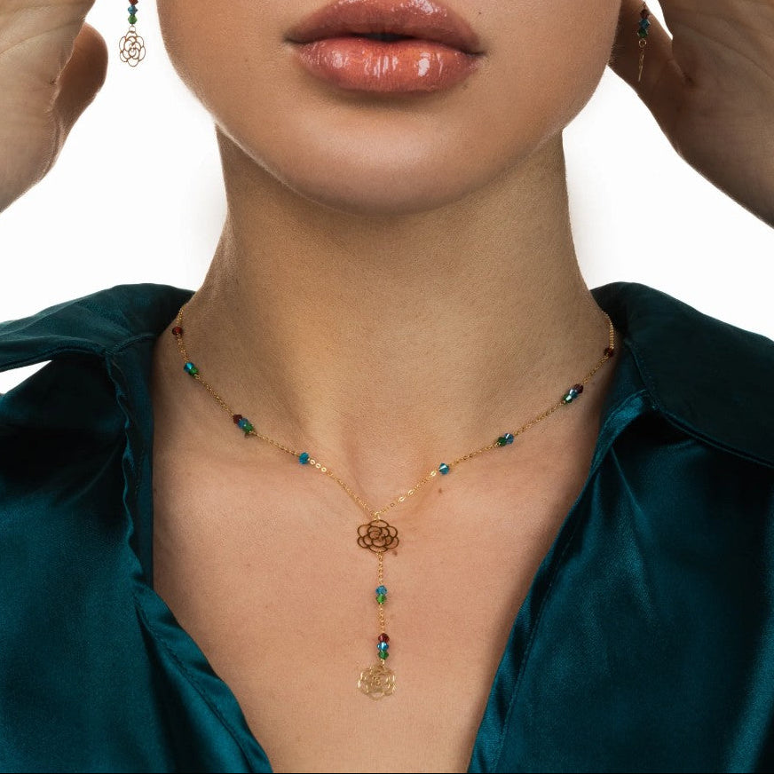 Close-up of a woman wearing a gold necklace with blue beads against a white background
