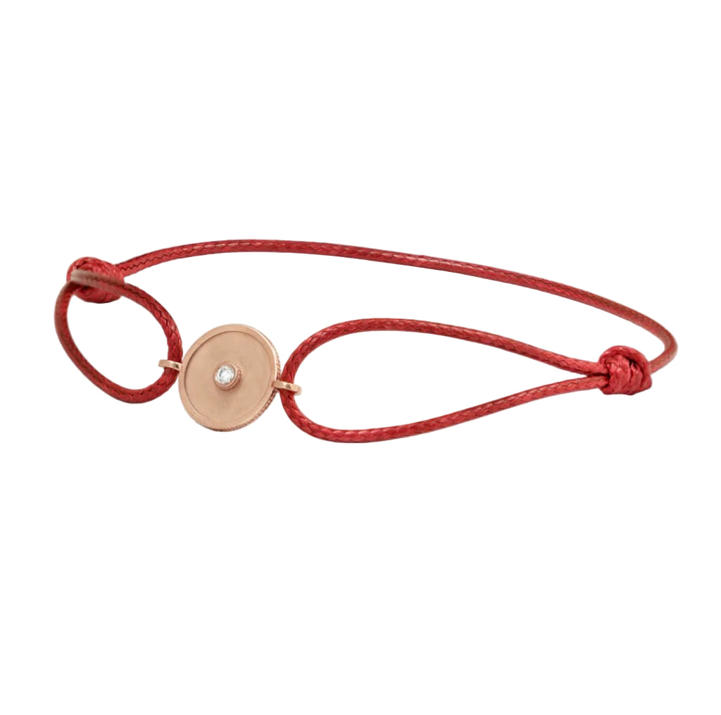 Red bracelet with a gold circular charm on a white background