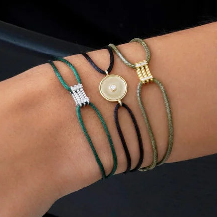 Multiple bracelets with various designs on a wrist against a dark background
