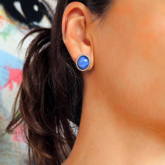 Close-up of an ear wearing a blue earring with a blurred background