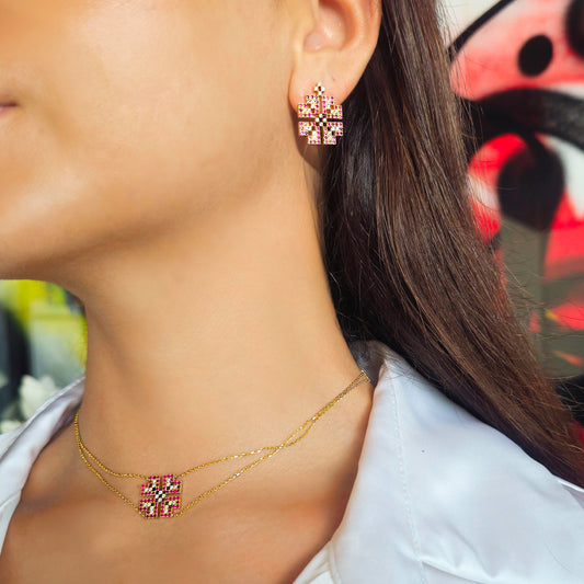 Close-up of a person wearing gold earrings and necklace with colorful background