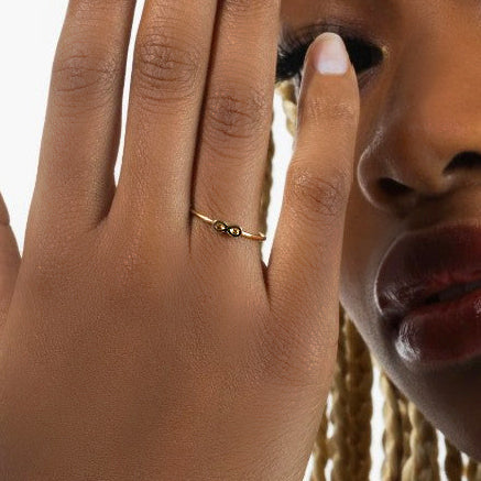 Close-up of a hand wearing a gold ring with a blurred background