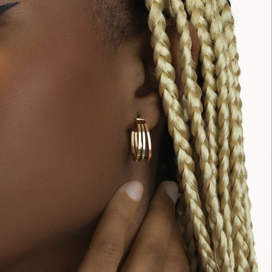 Close-up of a person wearing gold hoop earrings with braided hair.