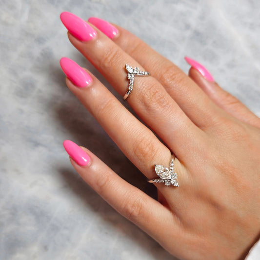 Hand with pink nails wearing two diamond rings on a gray background