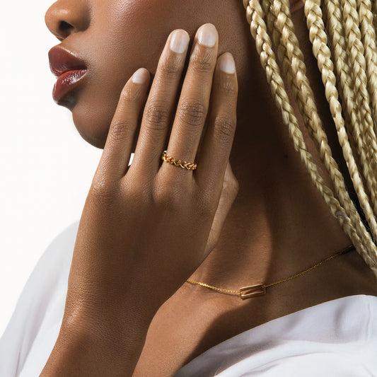 Close-up of a woman's hand with gold jewelry on a neutral background