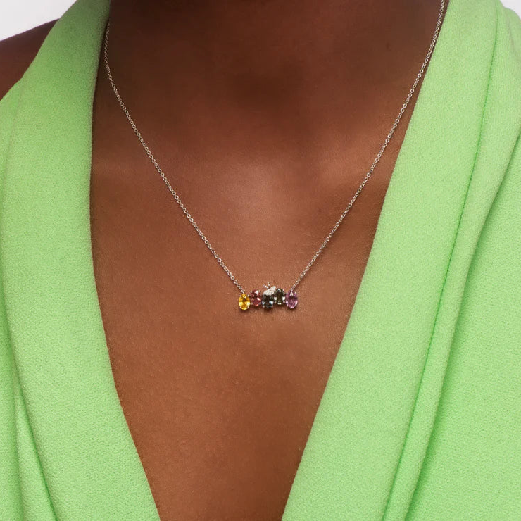 Necklace with multicolored gemstones worn by a person in a green outfit