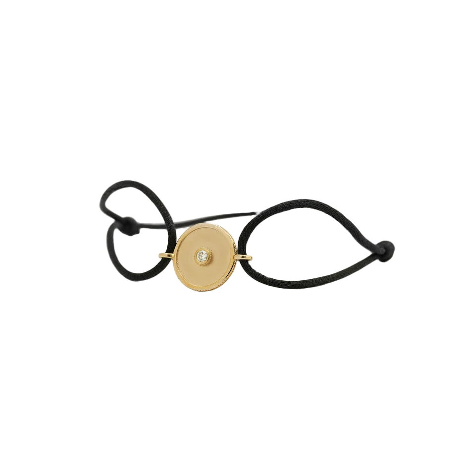 Black bracelet with a gold circular charm on a white background
