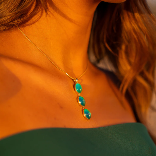Necklace with green gemstones worn by a person in an orange top.