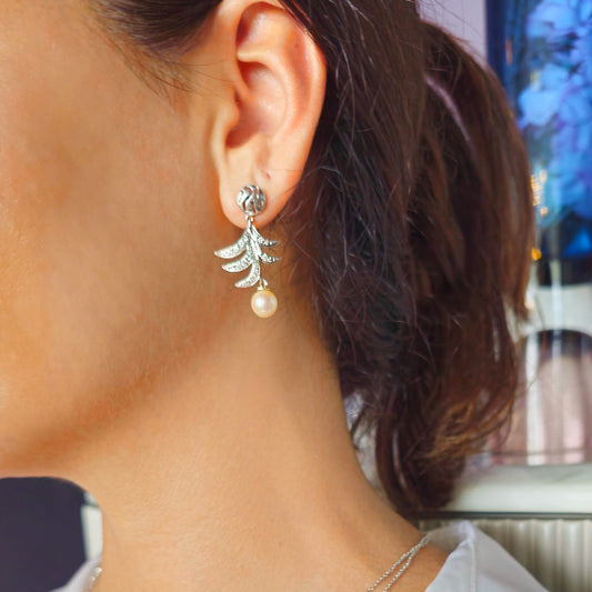 Close-up of a woman wearing a gold earring with a pearl drop.