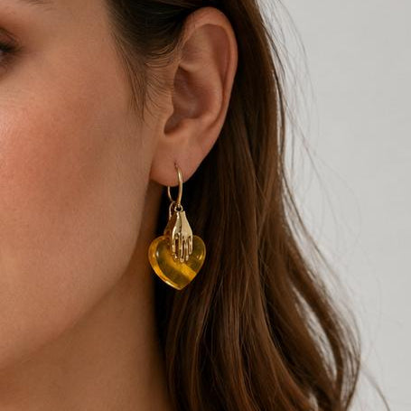 Woman wearing gold heart-shaped necklace and earrings against a neutral background