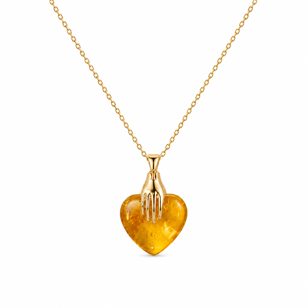 Gold necklace with a heart-shaped amber pendant on a white background
