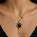 Gold necklace with a decorative key pendant on a person wearing a black top.