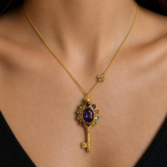 Gold necklace with a decorative key pendant on a person wearing a black top.