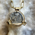 Gold necklace with a silver coin pendant featuring an owl on a marble surface