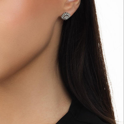 Close-up of a person wearing a gold earring with a clear gemstone.