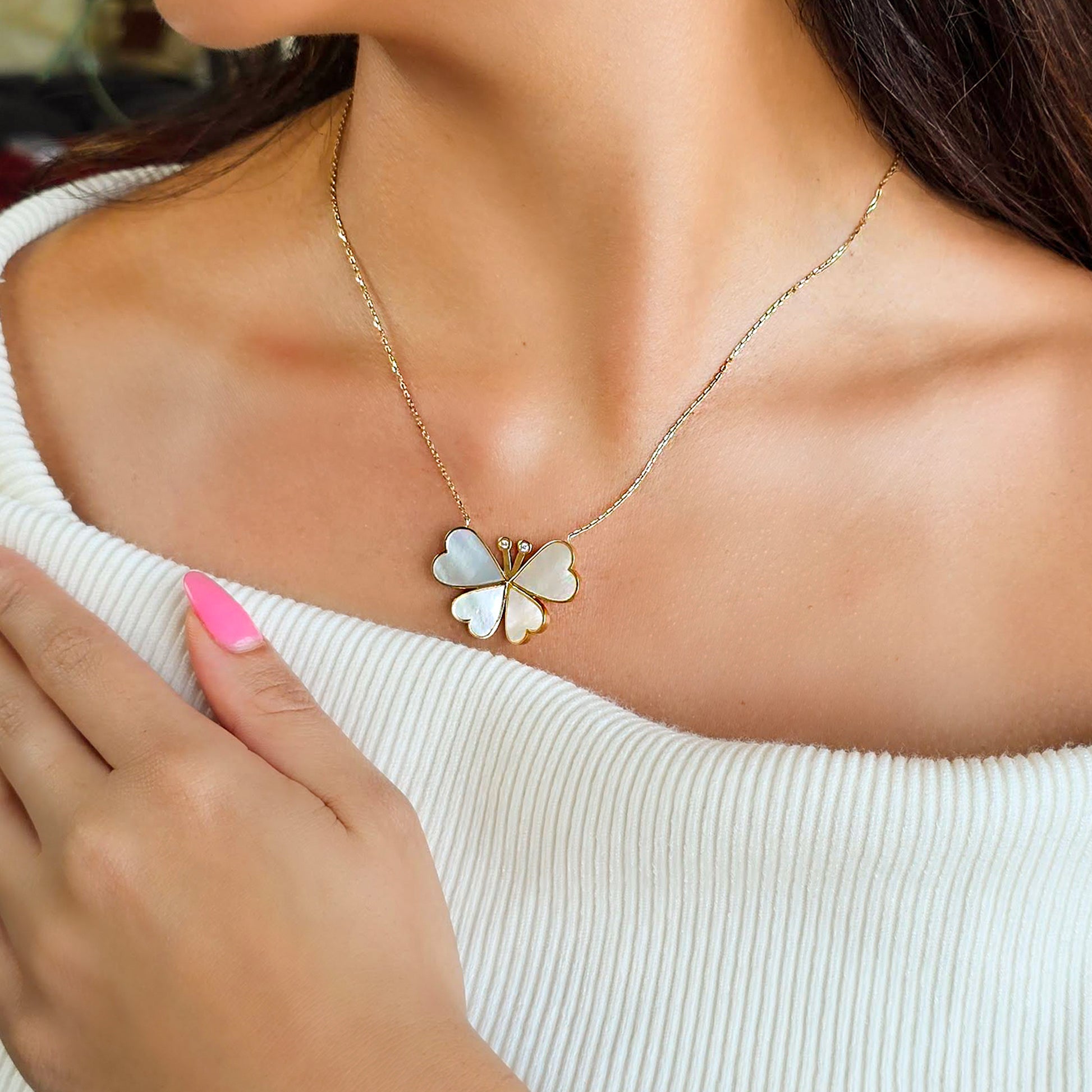 Butterfly-shaped necklace worn by a person with a blurred background