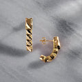Gold hoop earrings on a textured gray surface