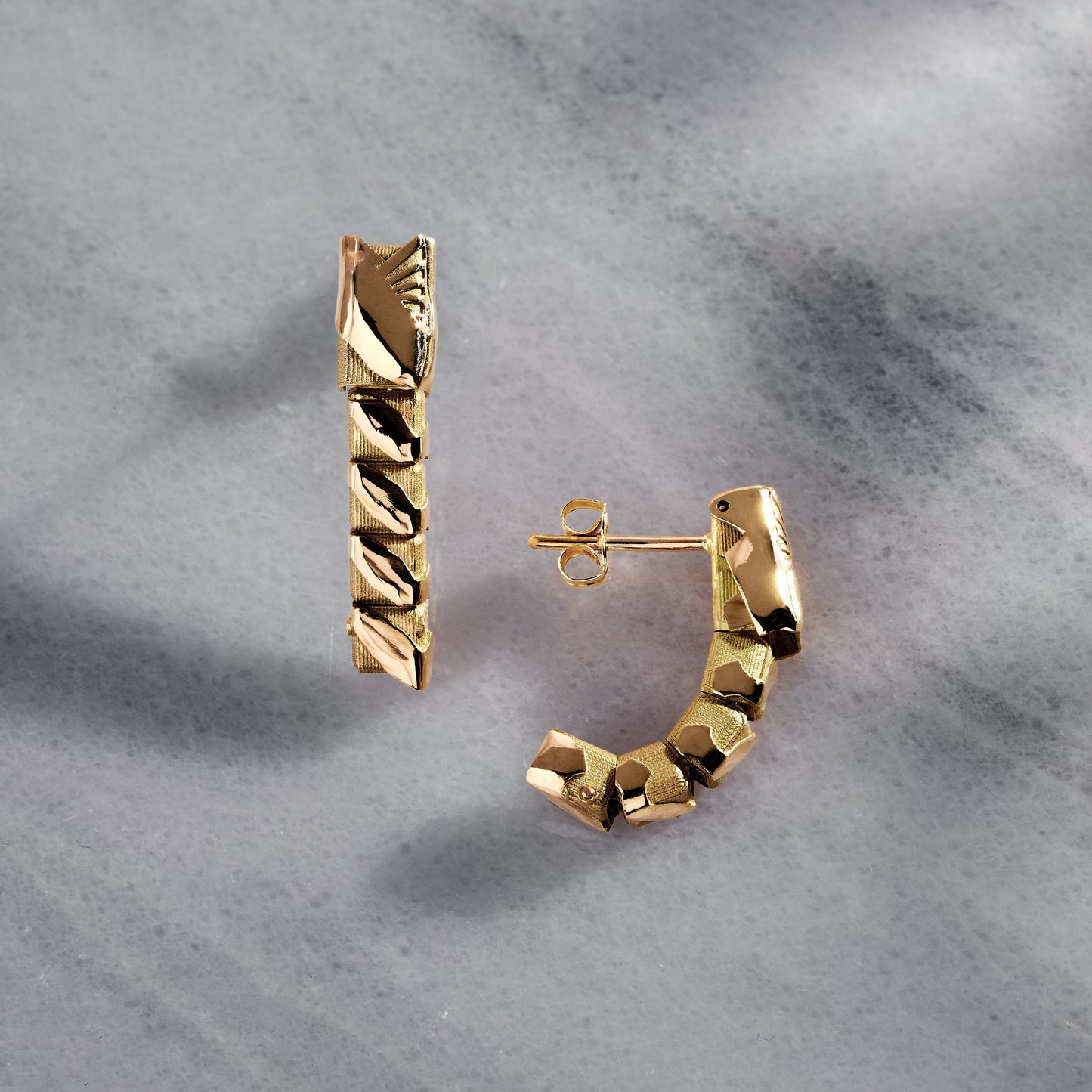 Gold hoop earrings on a textured gray surface