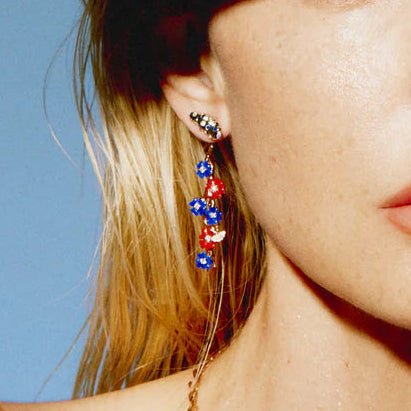 Close-up of a person wearing colorful earrings with a clear blue sky background