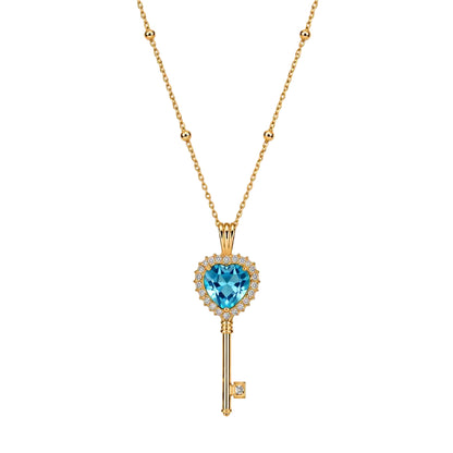 Gold key-shaped necklace with a blue gemstone on a white background