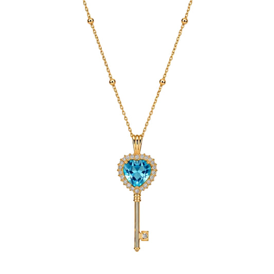 Gold key-shaped necklace with a blue gemstone on a white background