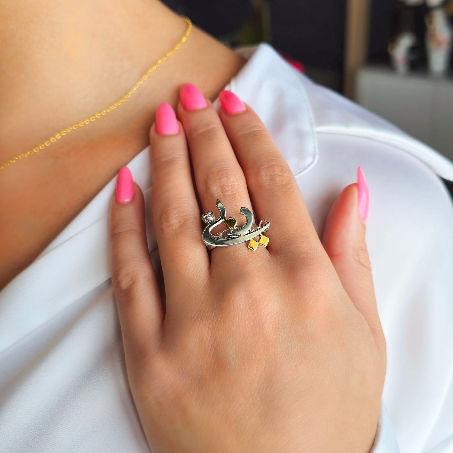 Hand with pink nail polish wearing a gold ring on a white background