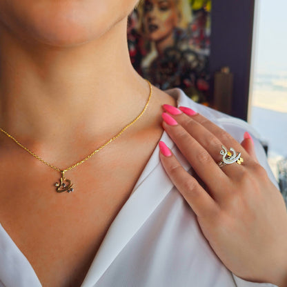 Gold necklace and ring on a person with a blurred background