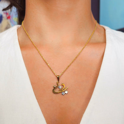Gold necklace with a unique pendant worn by a person against a neutral background