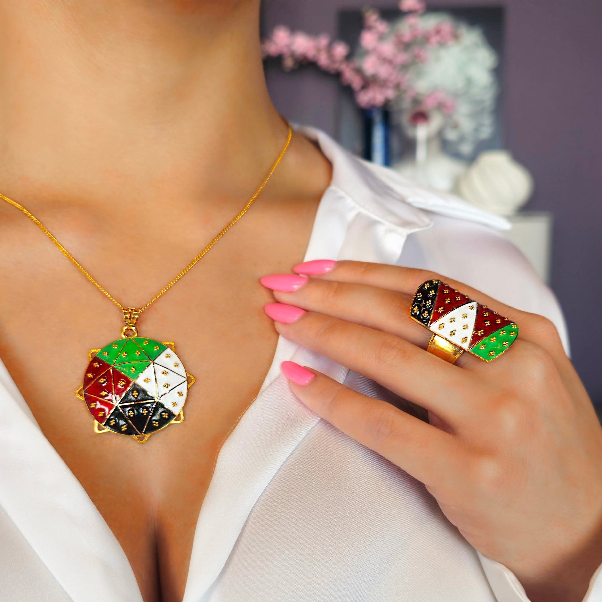 Gold necklace with colorful pendant and matching ring on a blurred background