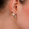 Close-up of an ear wearing colorful hoop earrings with a blurred background