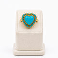 Turquoise heart-shaped ring on a white stand with a white background