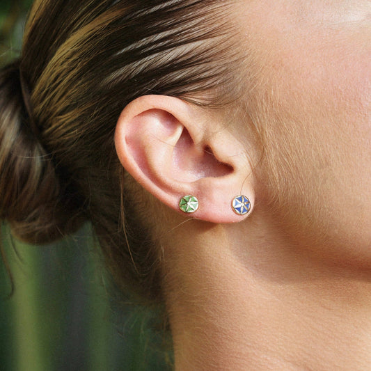 Close-up of a person wearing two earrings on an outdoor background