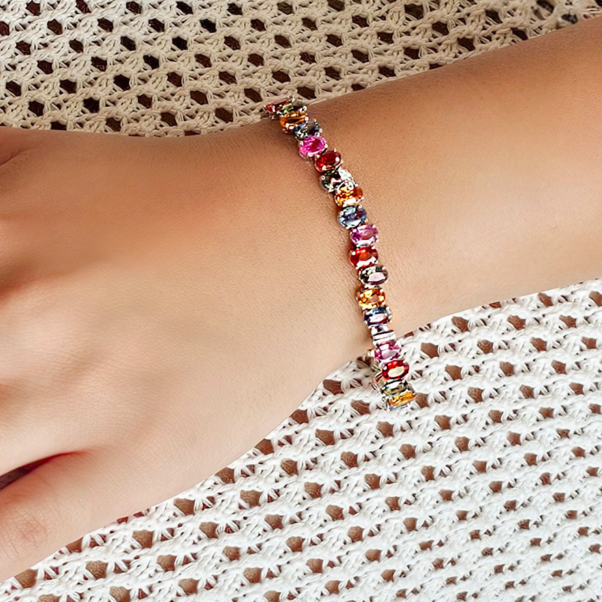 Multicolored beaded bracelet on a wrist with a textured fabric background