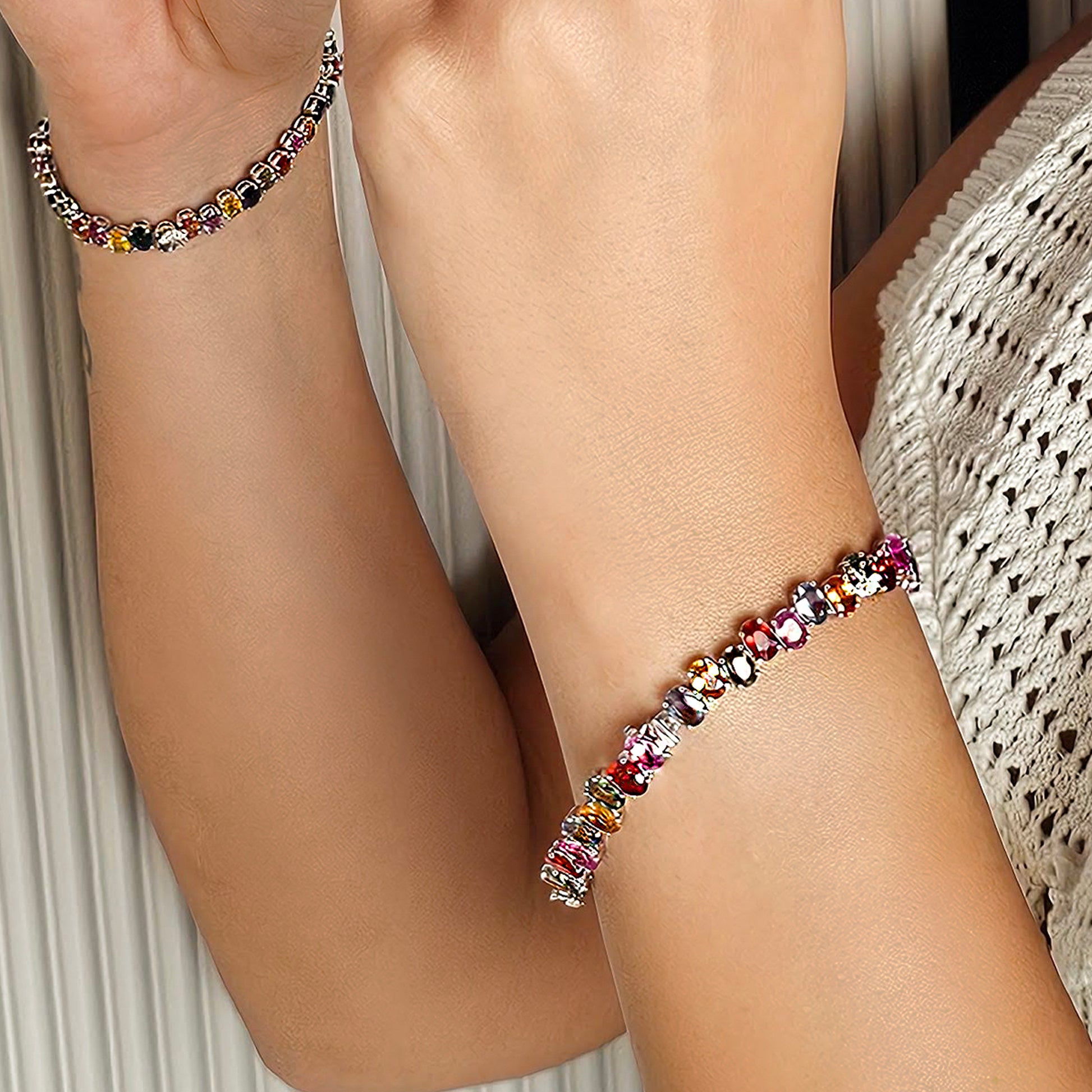 Multicolored beaded anklets on a person's legs with a neutral background