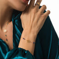 Close-up of a person wearing gold jewelry with a green satin garment.