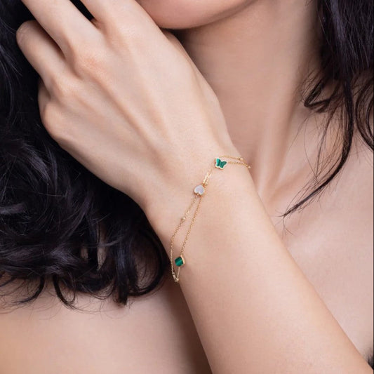 Close-up of a person wearing a delicate bracelet with green gemstones.