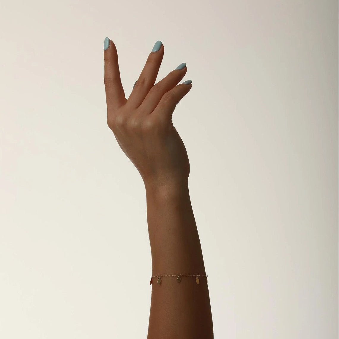 Hand with a gold bracelet on a plain background