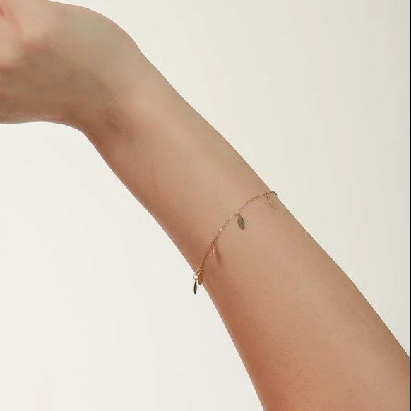 Gold bracelet on a person's wrist against a plain background