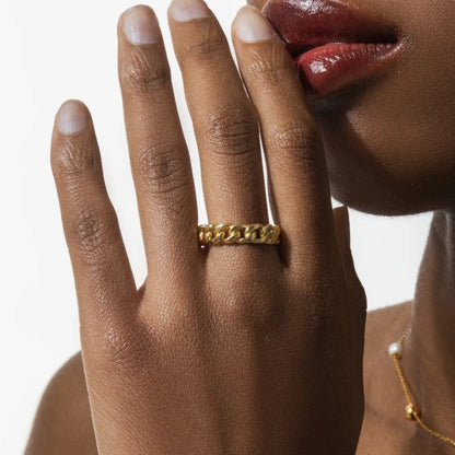 Hand wearing a gold chain ring with a blurred background