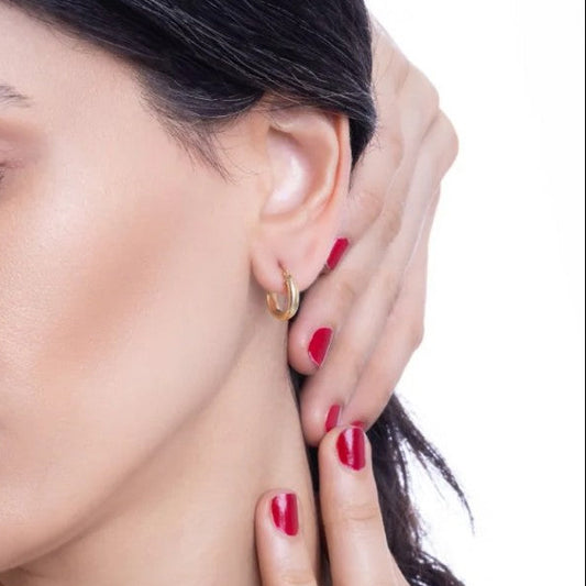 Close-up of a woman wearing a gold hoop earring with a neutral background