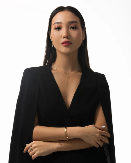 Woman wearing a black outfit with gold jewelry on a white background