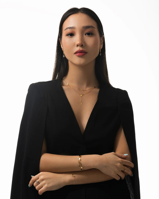 Woman wearing a black outfit with gold jewelry on a white background