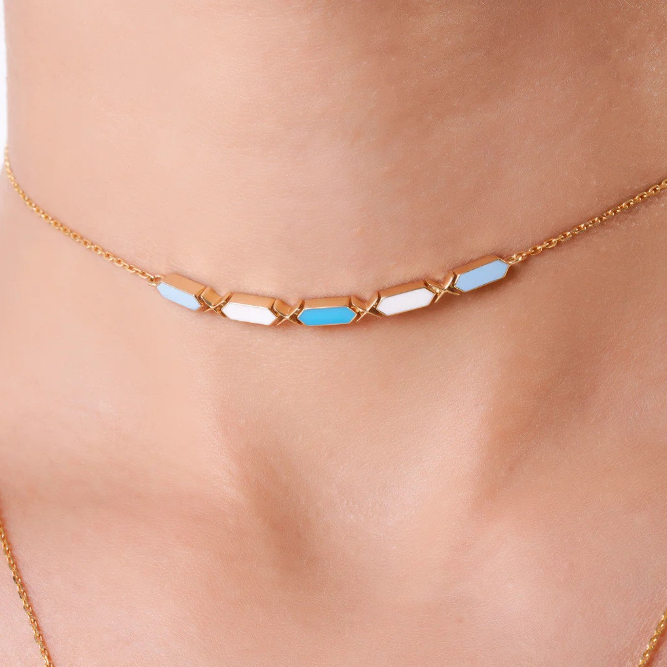 Necklace with blue and white geometric stones on a person's neck against a neutral background